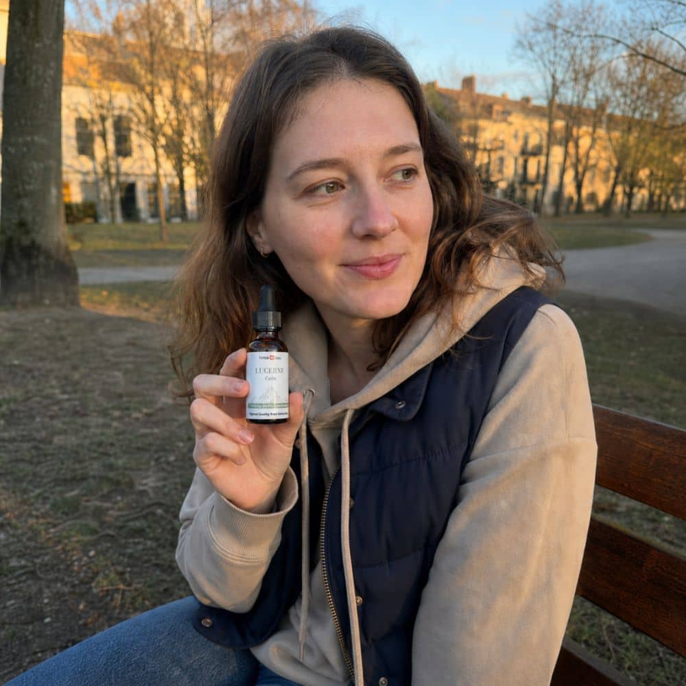 Mujer sosteniendo un frasco de aceite de CBD Lucerne al aire libre, en un parque