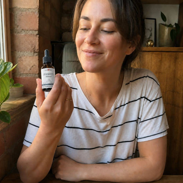 Mujer sosteniendo una botella de aceite de CBD de Zermatt en un entorno interior acogedor.